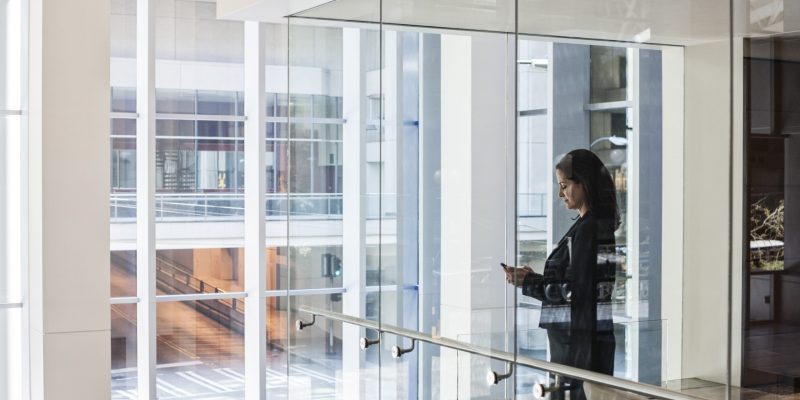 Businesswoman standing in a conference room window in a large business center.
